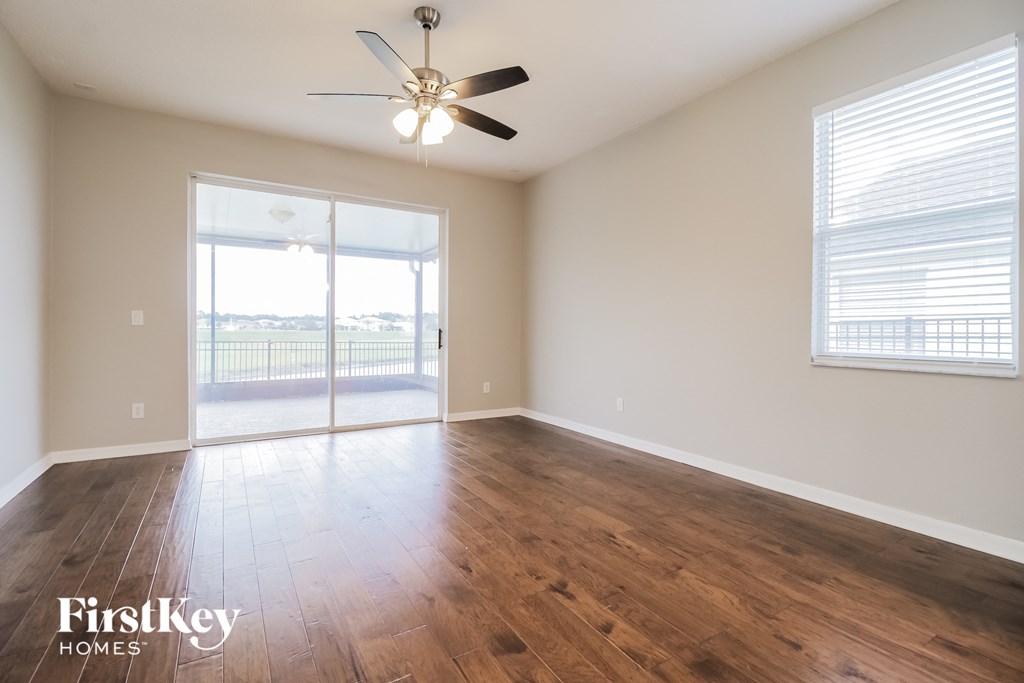 an empty living room with wood floors and a ceiling fan
