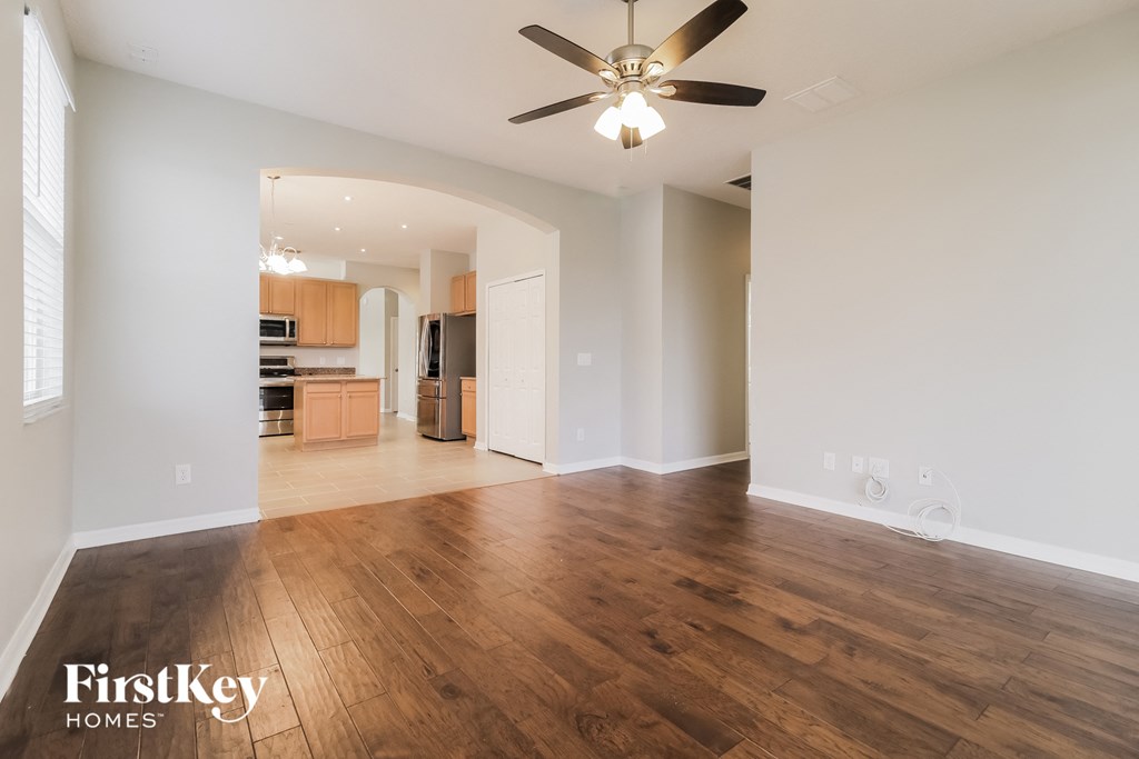 an empty living room with wood flooring and a ceiling fan
