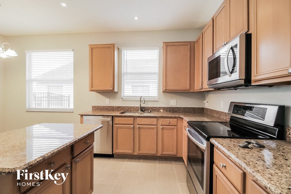 a kitchen with wooden cabinets and granite counter tops and a stove and microwave