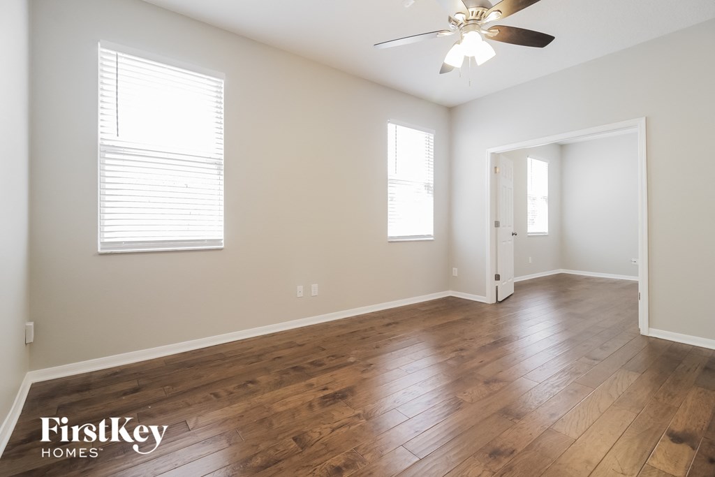 an empty living room with wood floors and a ceiling fan