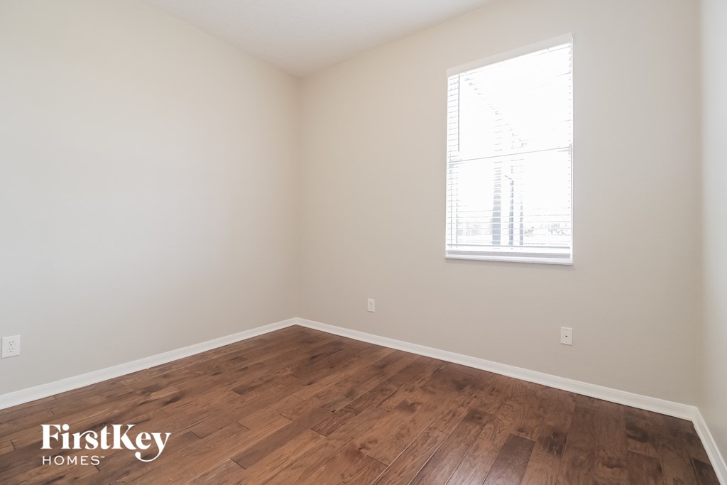 a bedroom with a wood floor and a window