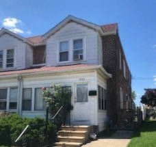 A white house with a red roof and a brick chimney.