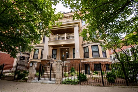 an old brick house with a wrought iron fence in front of it