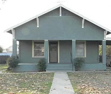 a green house with a sidewalk in front of it