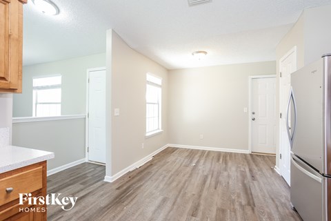 A kitchen with a refrigerator and wooden floors.