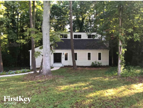 A house with a black roof is surrounded by trees.