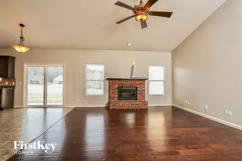 an empty living room with a fireplace and a ceiling fan