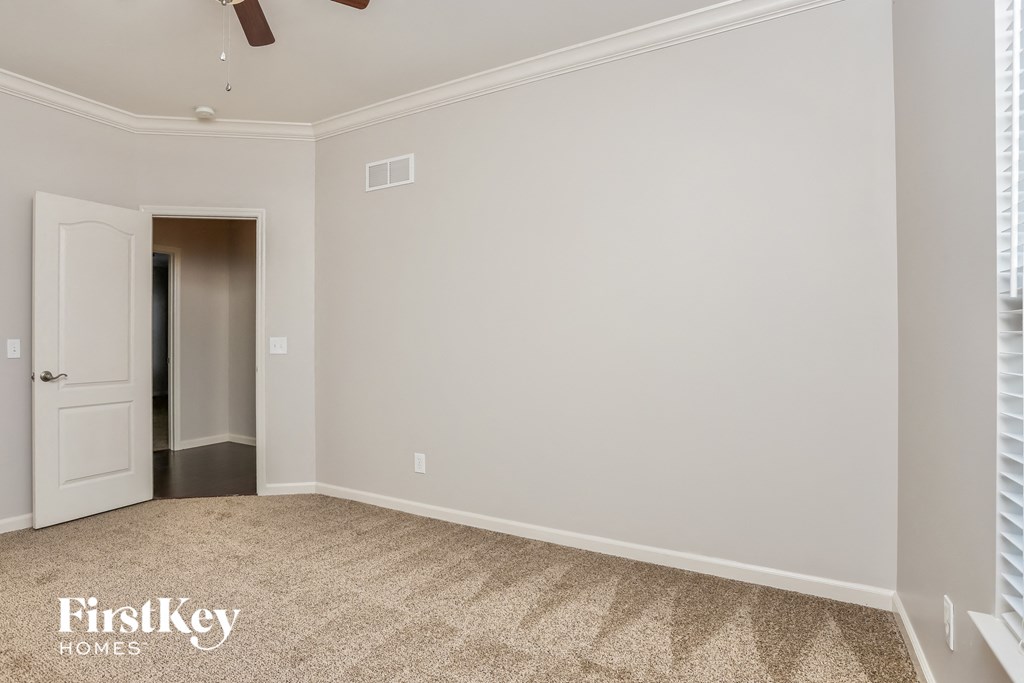 a bedroom with white walls and a white door and a carpeted floor