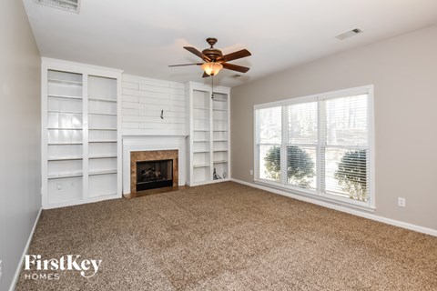 A spacious room with a fireplace and a ceiling fan.