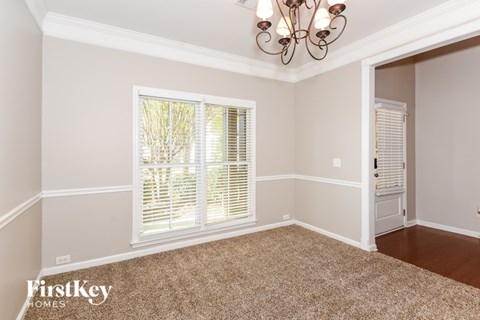 A room with a carpeted floor and a chandelier hanging from the ceiling.