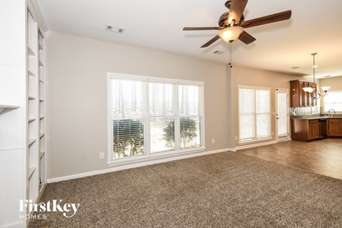 A spacious room with a ceiling fan and a carpeted floor.