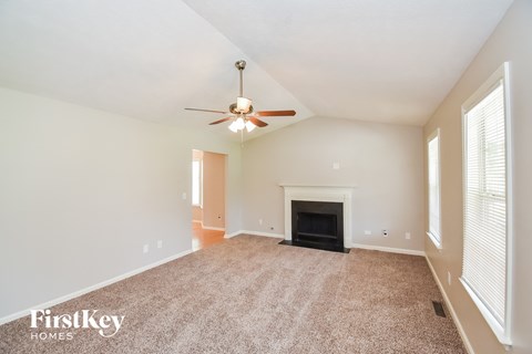 an empty living room with a fireplace and a ceiling fan