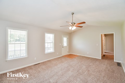 a living room with carpet and a ceiling fan