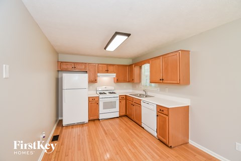 a kitchen with wood flooring and white appliances and wooden cabinets