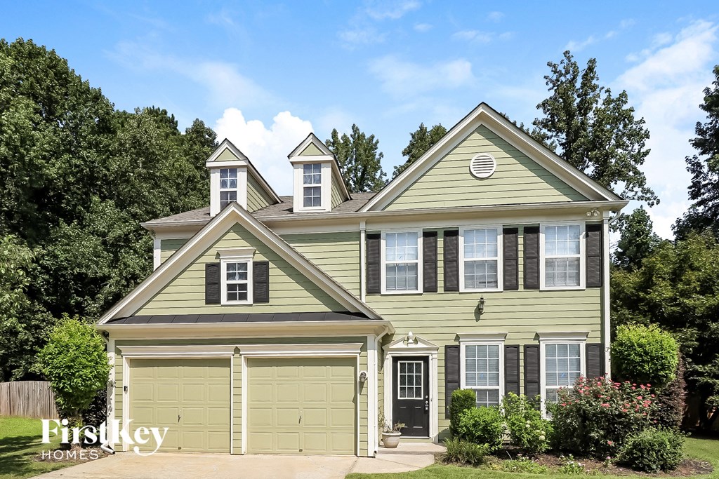 the front of a green house with white windows and a garage