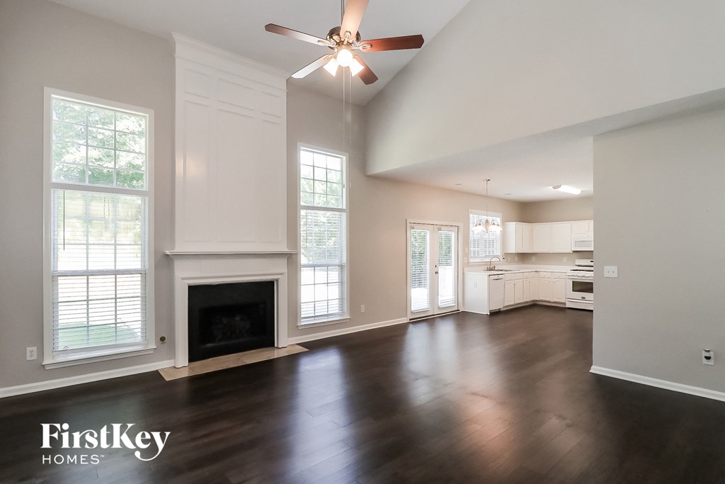 an empty living room with a fireplace and a ceiling fan