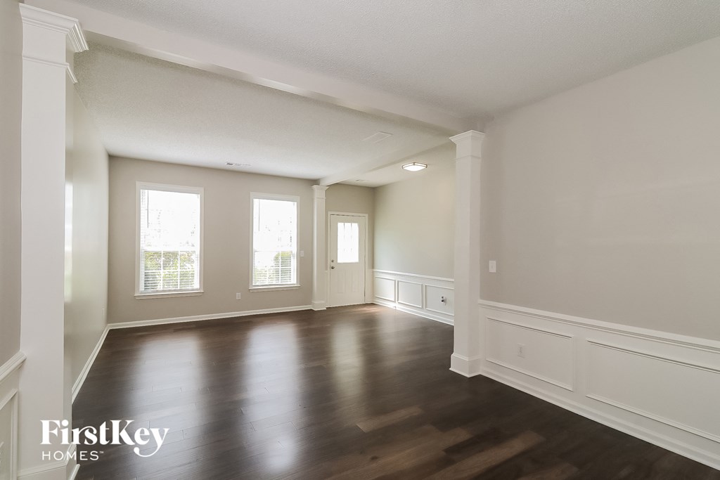 an empty living room with wood floors and white walls