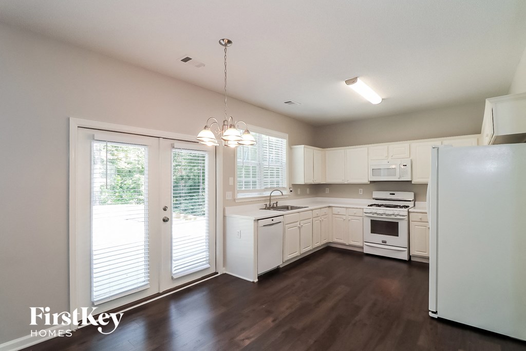 a kitchen with white cabinets and white appliances and a sliding glass door