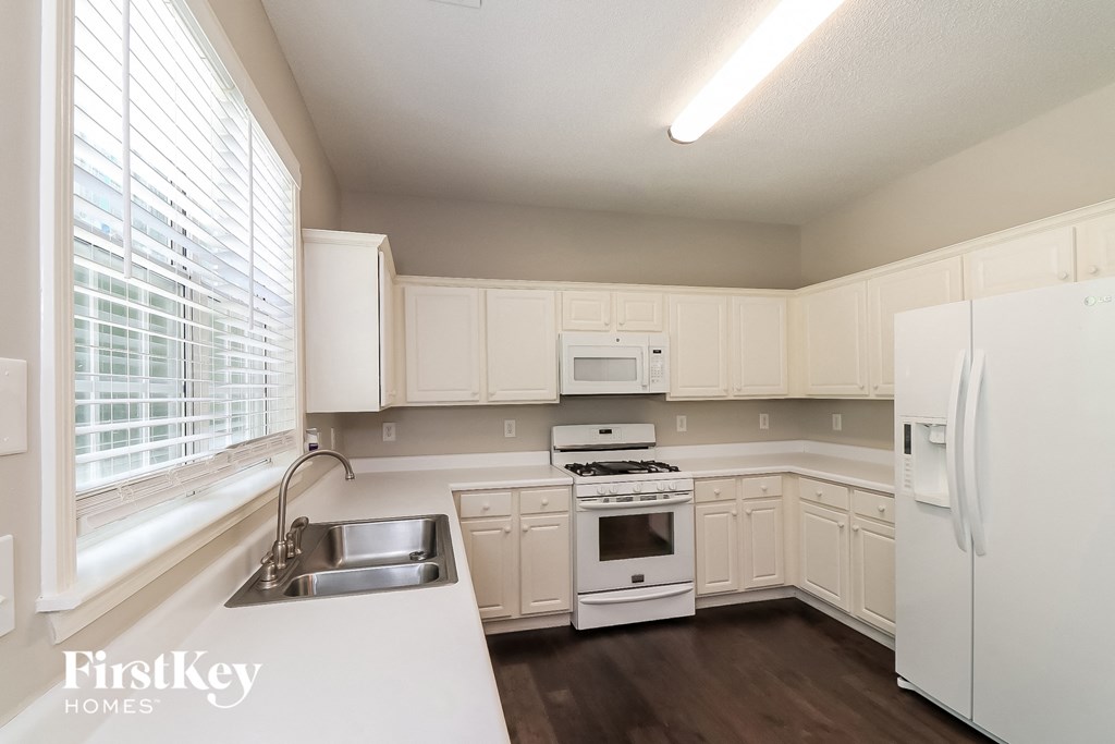a kitchen with white cabinets and white appliances and a sink
