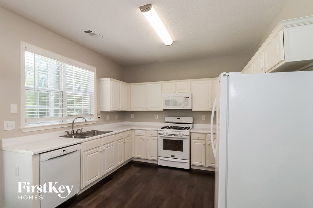 a kitchen with white cabinets and white appliances and a window