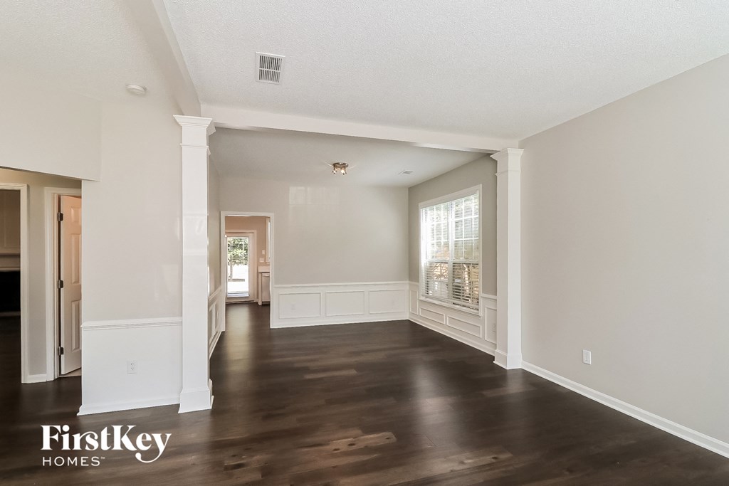 a living room with white walls and wood floors and a large window