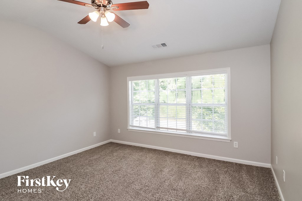 the master bedroom has a large window and carpeted flooring