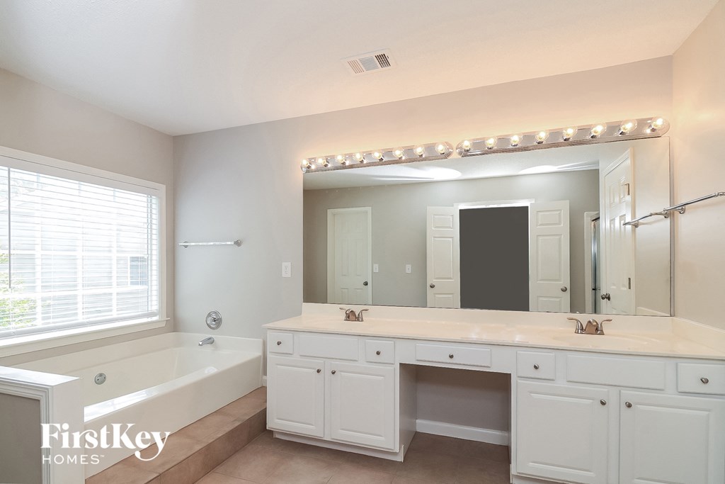 a white bathroom with a large mirror and a tub and sink