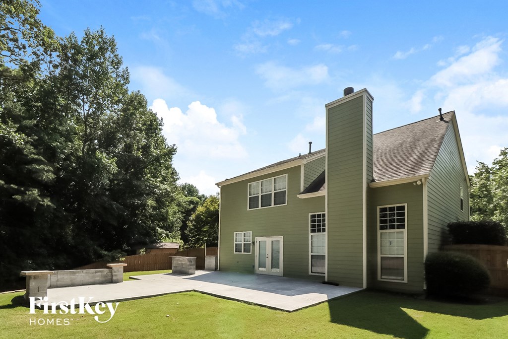 a green house with a driveway and a tree