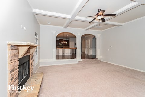 A spacious living room with a fireplace and a ceiling fan.