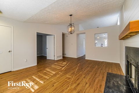 A spacious living room with wooden floors and a fireplace.
