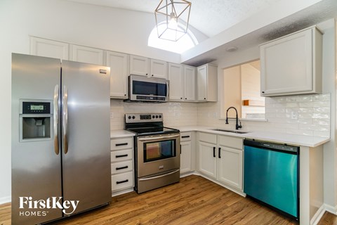 A kitchen with a stainless steel refrigerator and a stove top oven.