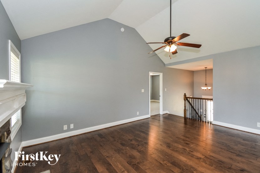 A spacious room with a ceiling fan and hardwood floors.