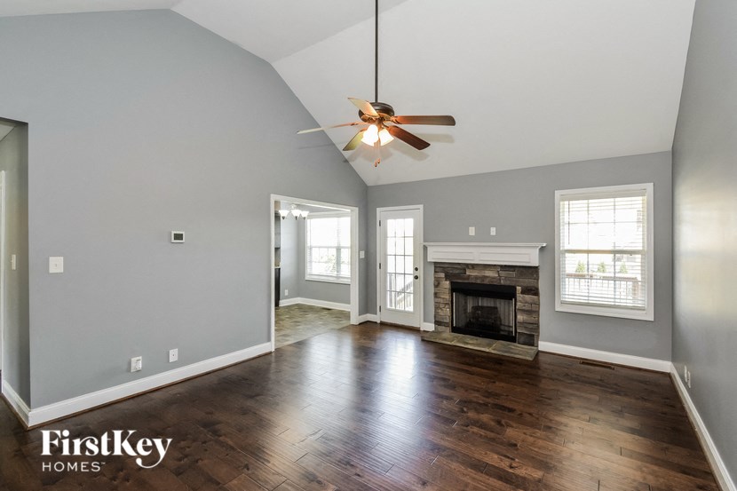 A spacious living room with wood flooring and a fireplace.