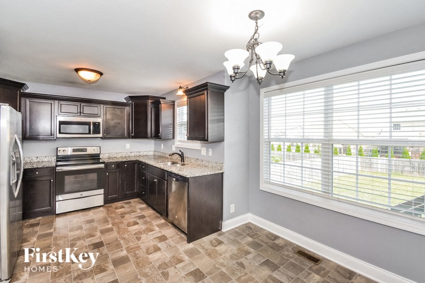 A kitchen with a tile floor and a window with blinds.