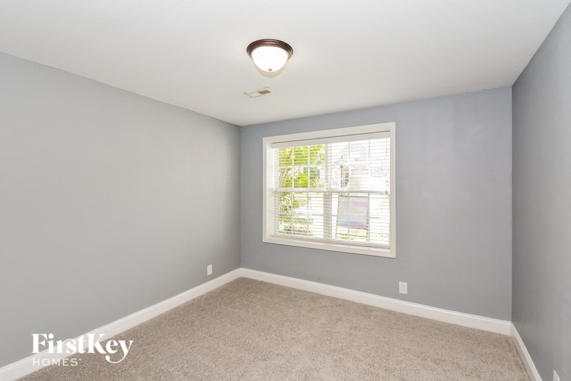 A room with a window and a carpeted floor.