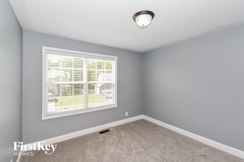 A room with a window and a carpeted floor.