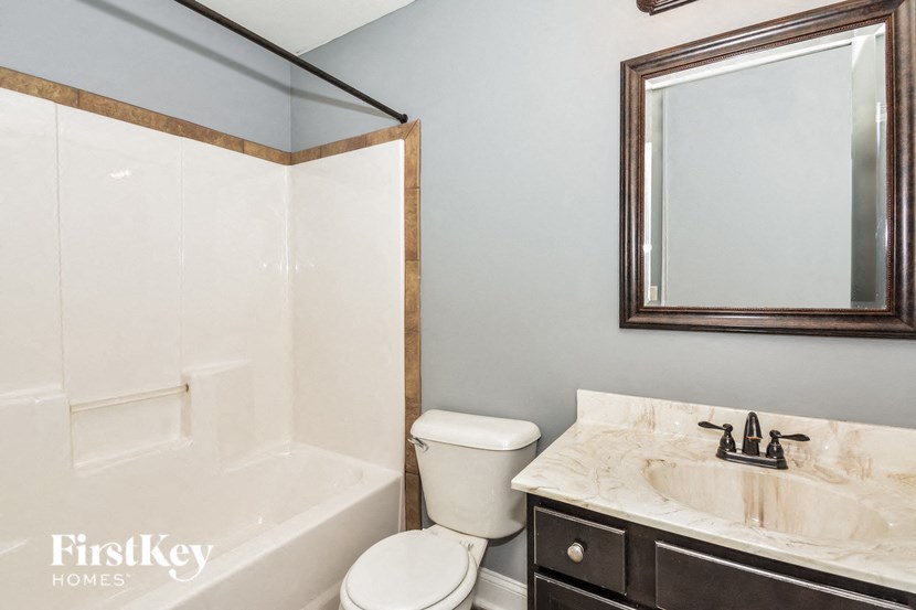 A bathroom with a toilet, sink and mirror.