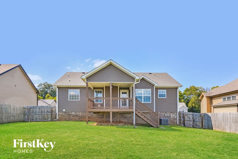 A house with a brown roof and a deck in the front yard.