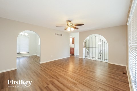 A spacious room with wooden floors and a ceiling fan.