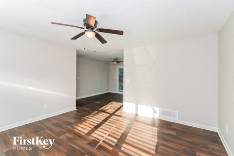an empty living room with a ceiling fan and wood floors
