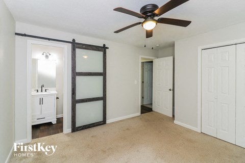a bedroom with a ceiling fan and a bathroom with a closet and a sink