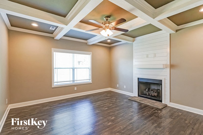 an empty living room with a ceiling fan and a fireplace