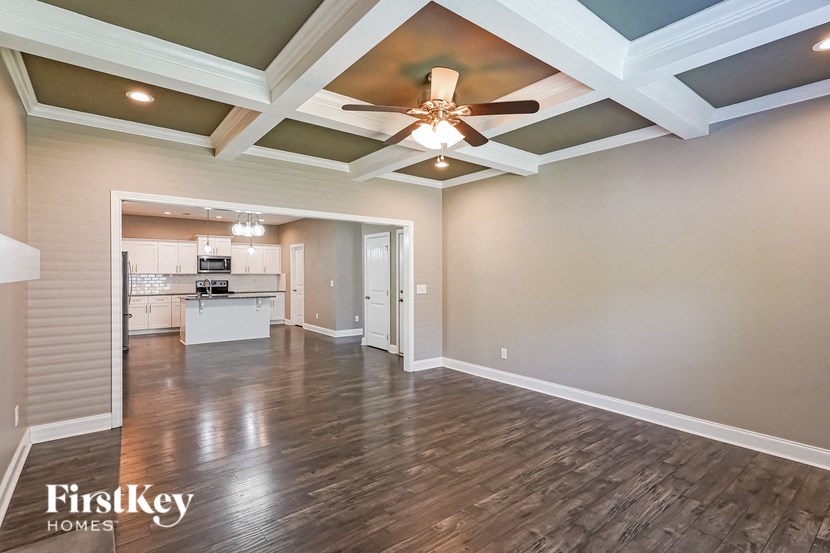 an empty living room with a ceiling fan and a kitchen