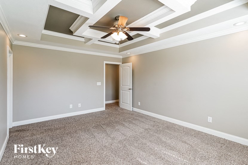 a living room with a ceiling fan and a carpet