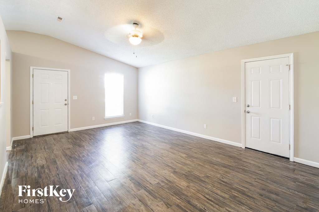 an empty living room with wood flooring and white walls