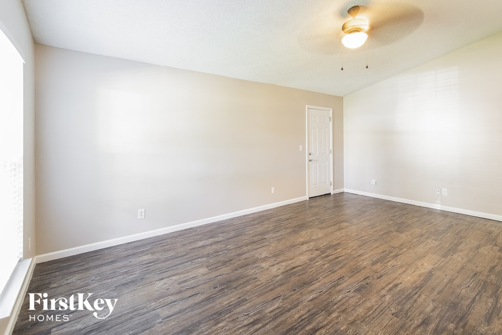 the spacious living room with wood flooring and white walls