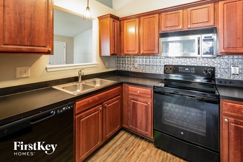 a kitchen with wood cabinets and black appliances and a sink