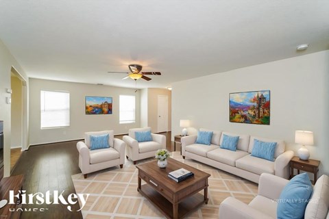 A living room with a couch, chairs, and a painting on the wall.