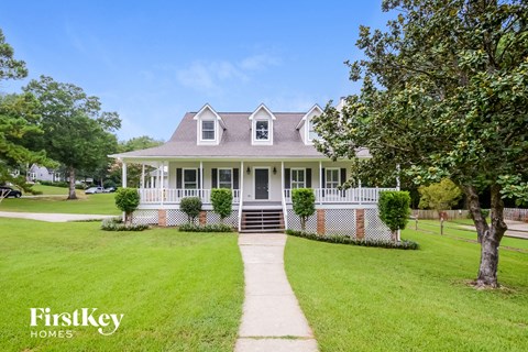 A house with a white picket fence and a tree in front.