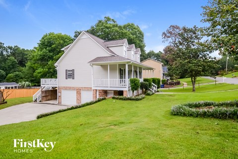A white house with a green lawn in front of it.